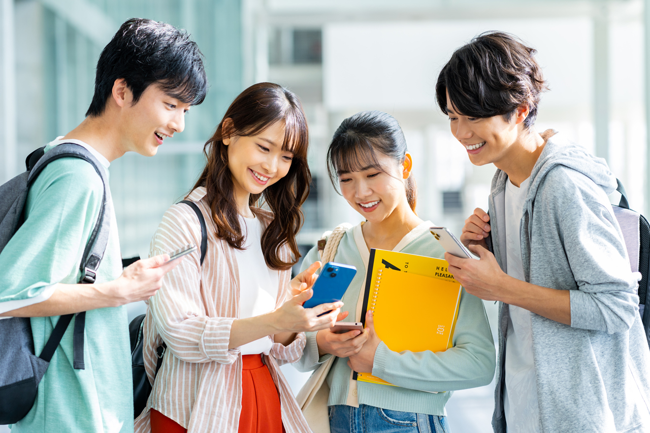 男女の大学生がスマホ見て笑っている楽しそうなイメージ