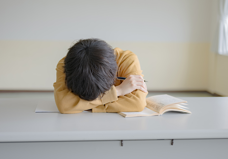 机に伏せている男子学生